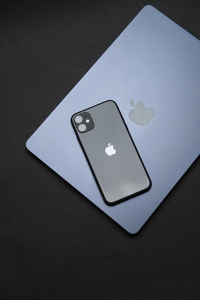 Modern Apple iPhone and MacBook on black surface, symbolizing sleek technology.